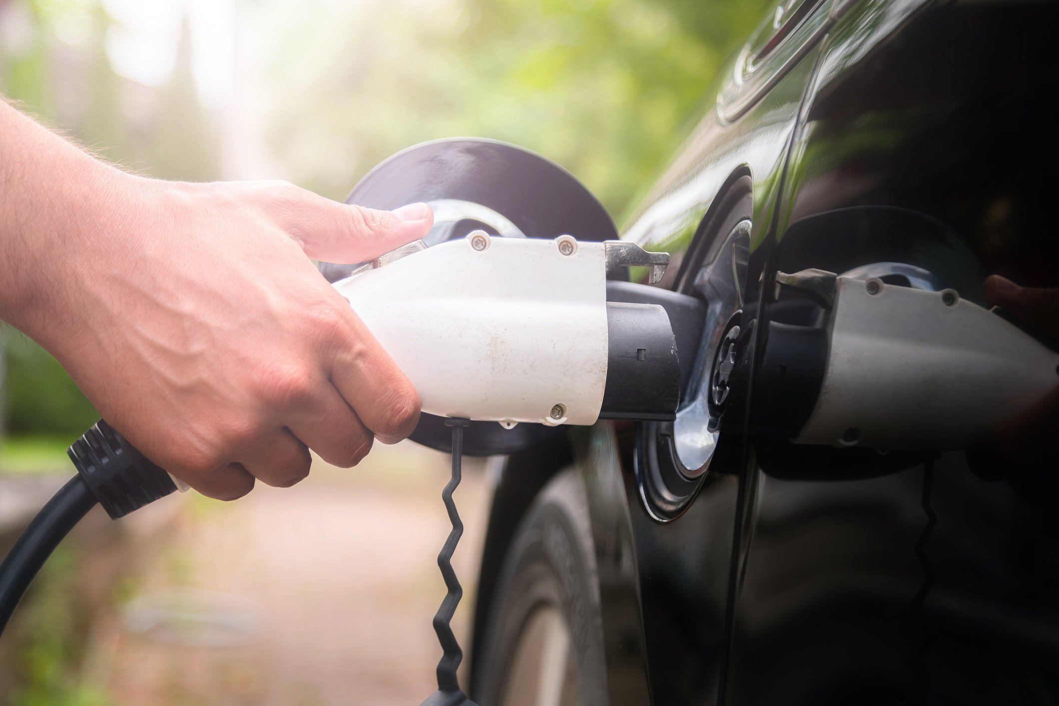 Man inserts charging plug into an electric car.