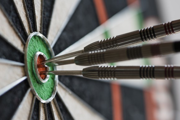 Three darts in the center ring of a dartboard.