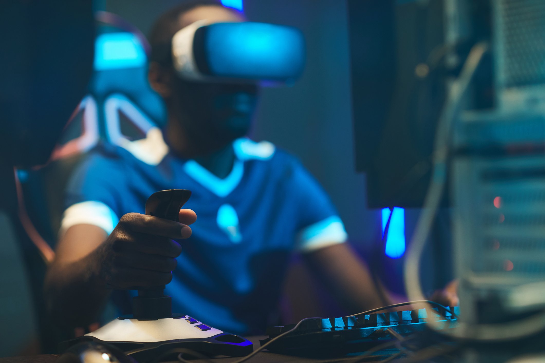 Young man playing a video game using a joystick and VR goggles.