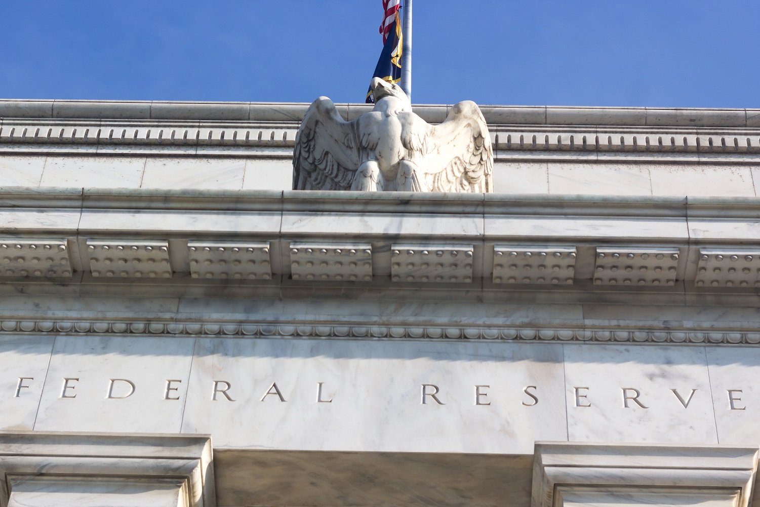 Federal Reserve building awning, showing engraved name and eagle with flag above.