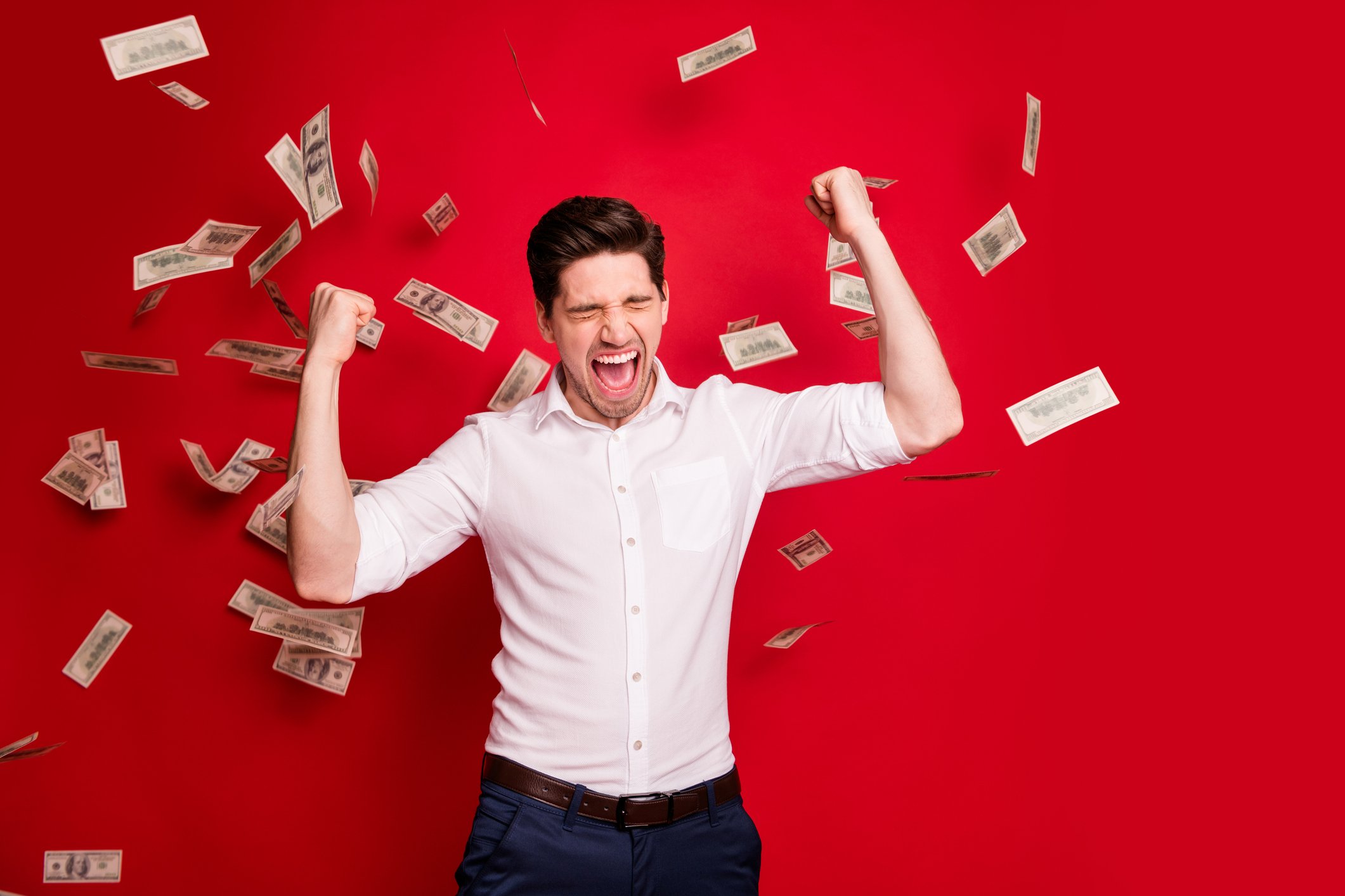 A man jumping for joy as $100 bills fall from above.