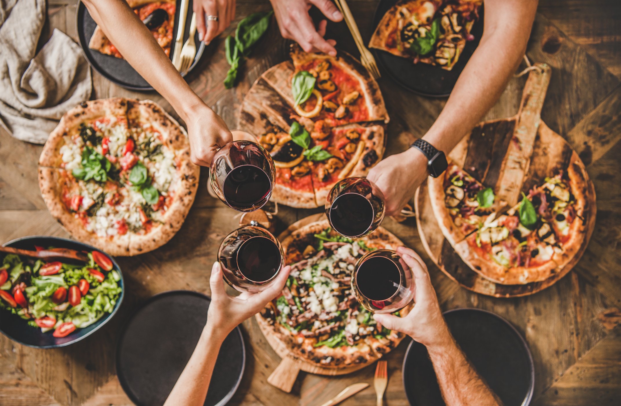 Four people enjoying pizzas and drinks