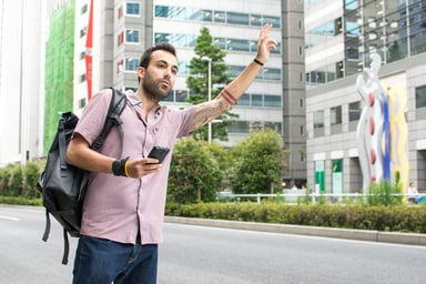 Young man holding a cellphone hailing a ride