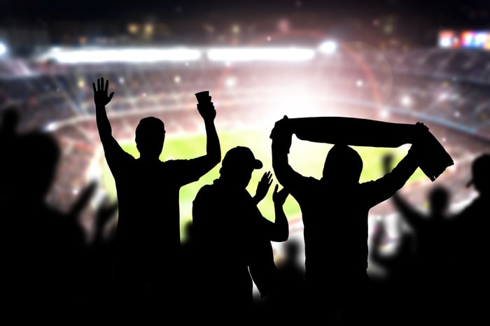 silhouette of fans at lit up football stadium