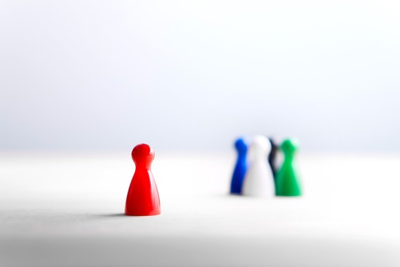 A figurine stands separated from a crowd of several other figurines.