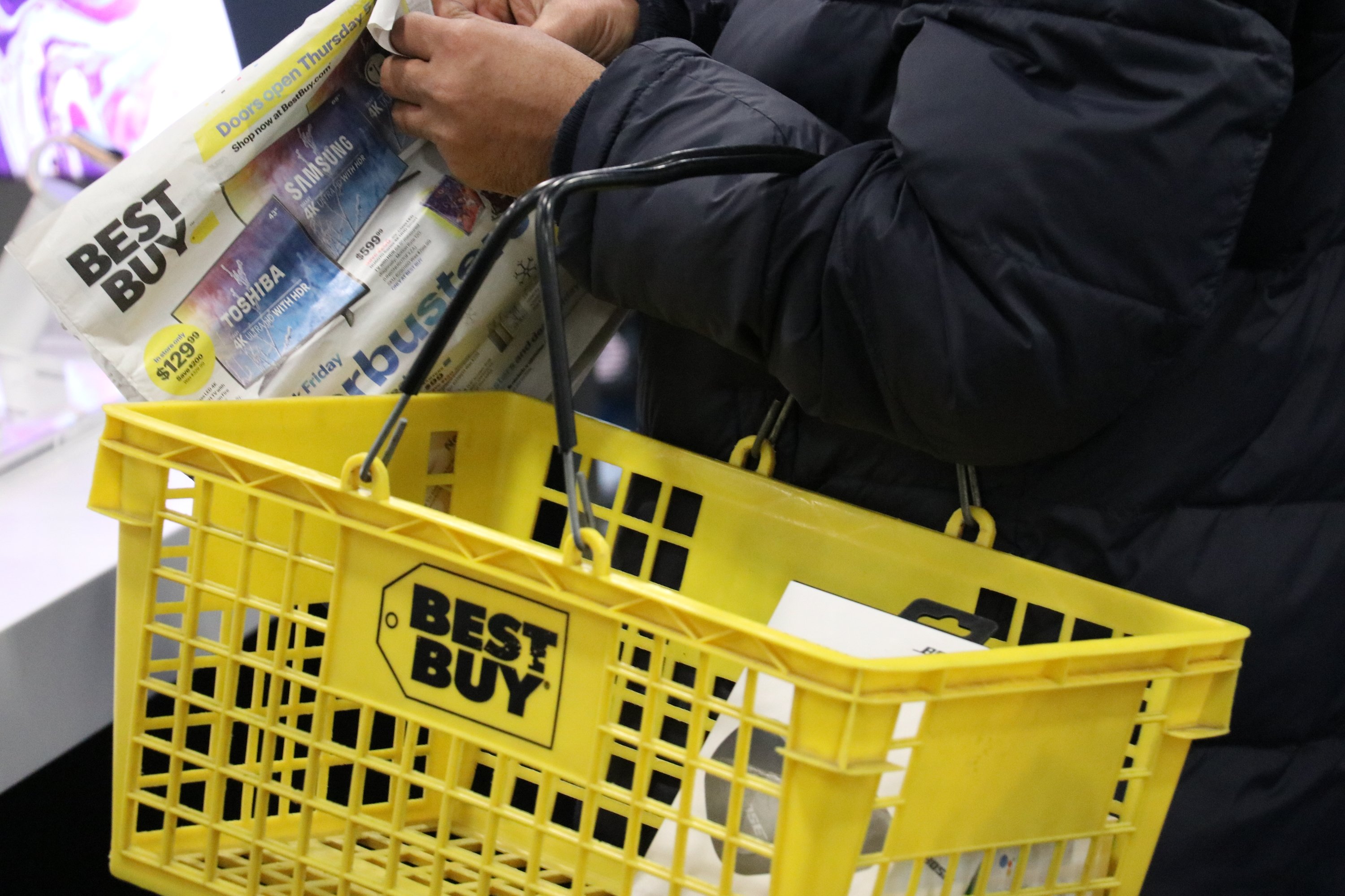 Best Buy shopper with basket and advertising flyer.