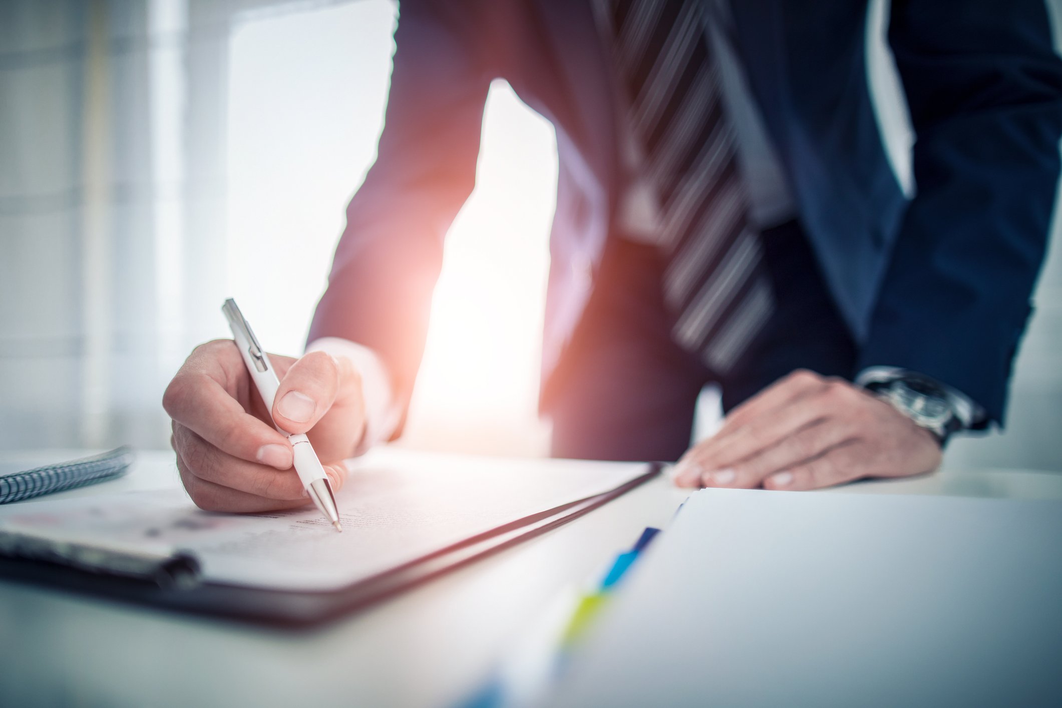 Person in suit studying papers on a clipboard.
