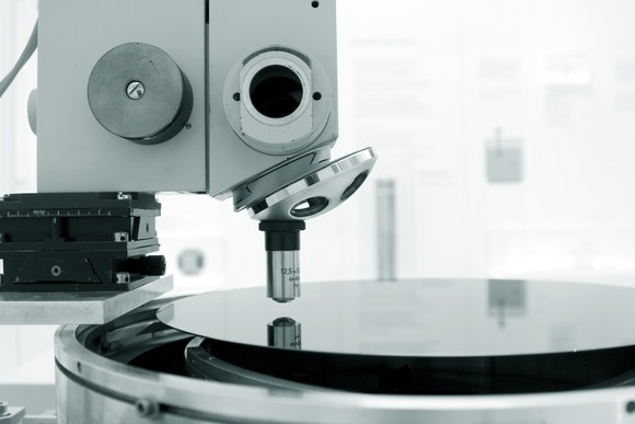 View of  semiconductor equipment and a wafer viewed from the side in a white room. 