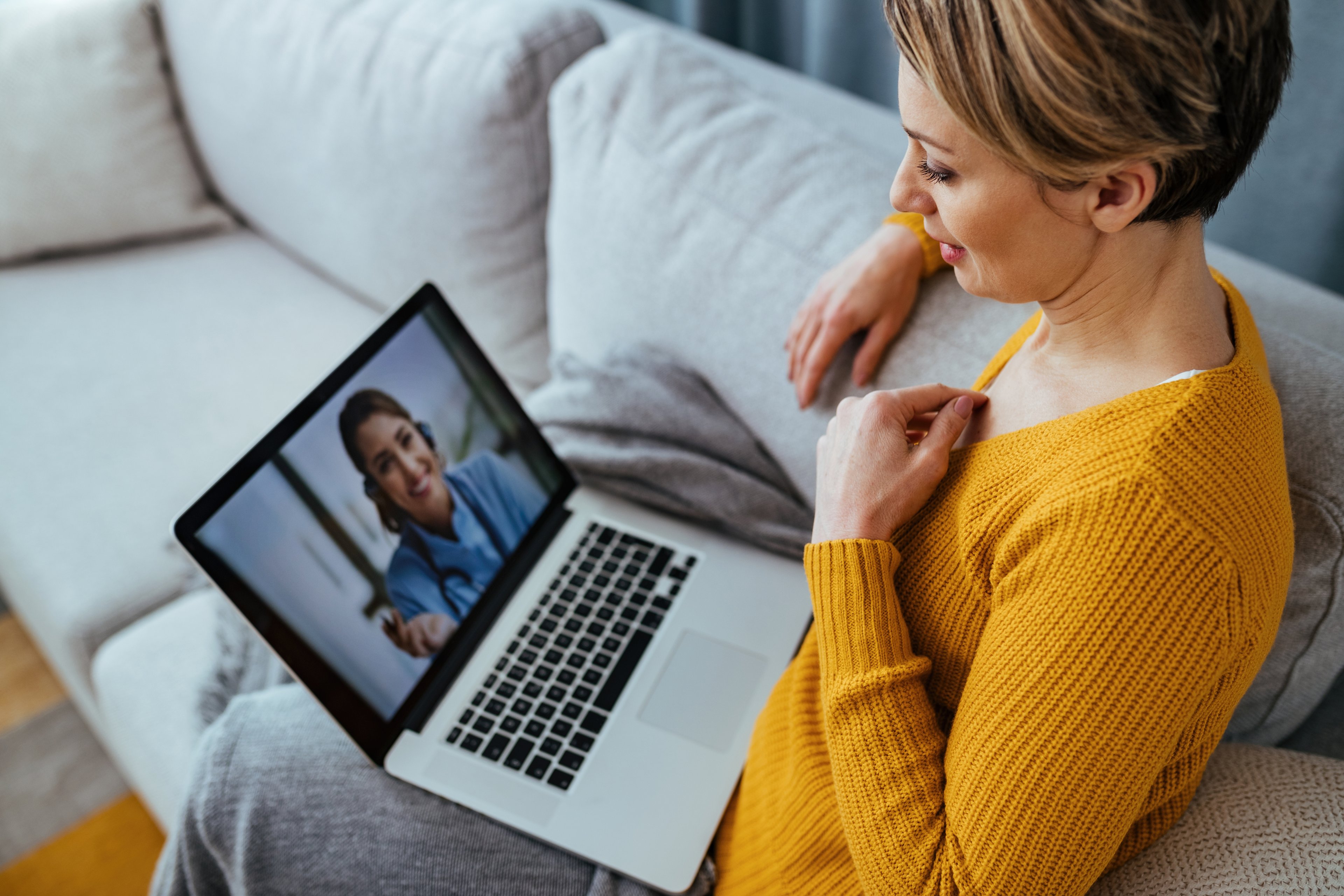 Woman consulting with doctor via video call at home. 