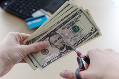 A person cutting a set of U.S. currency bills