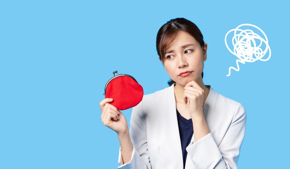 A young person in a business suit looks contemplatively at a coin purse. 