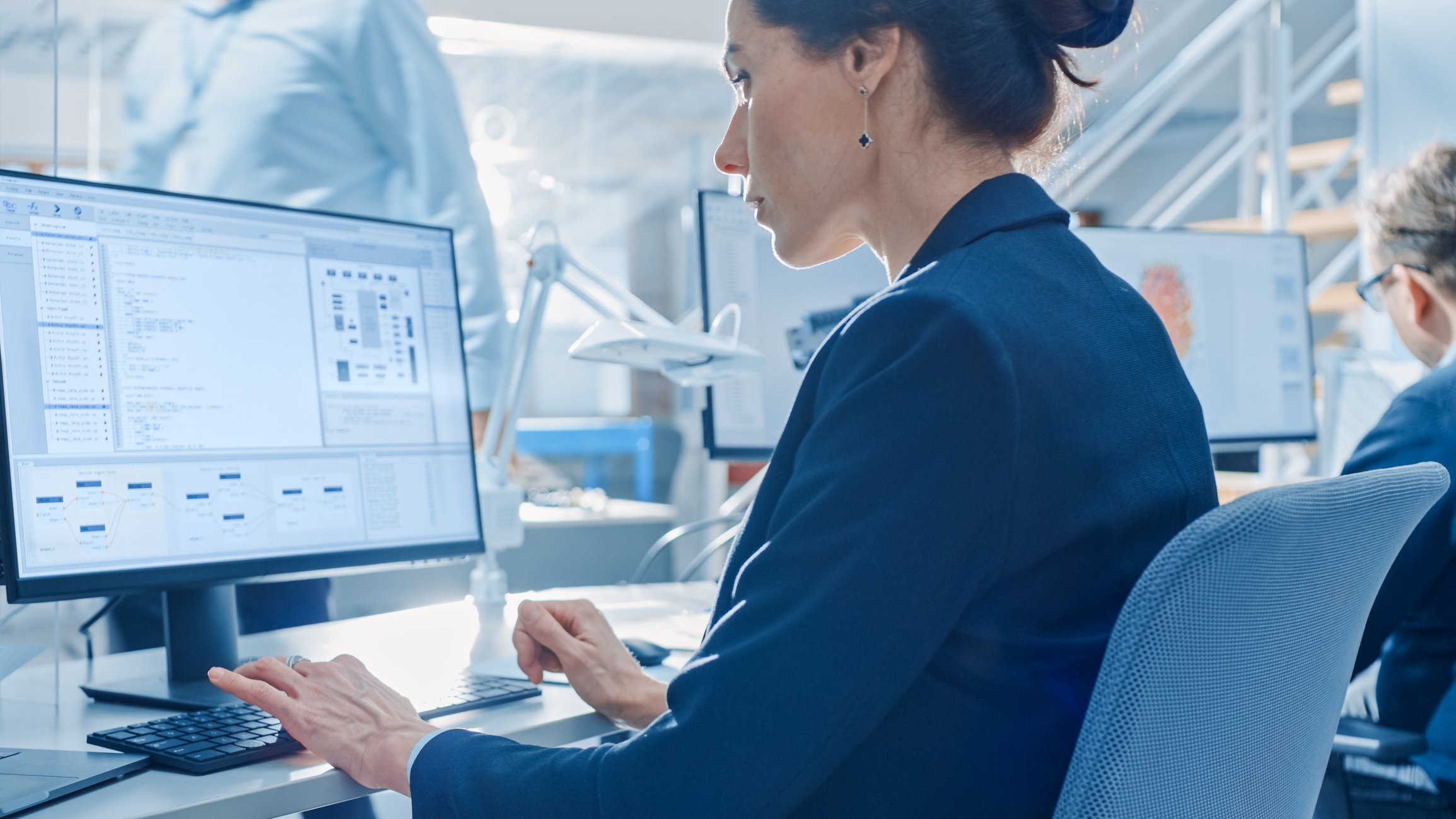 A female engineer works on computer-assisted design software in a contemporary engineering firm office.
