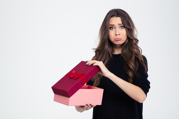 A frowning young woman holding a present.