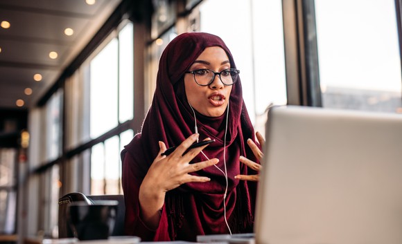 A young woman takes a video call on her laptop.
