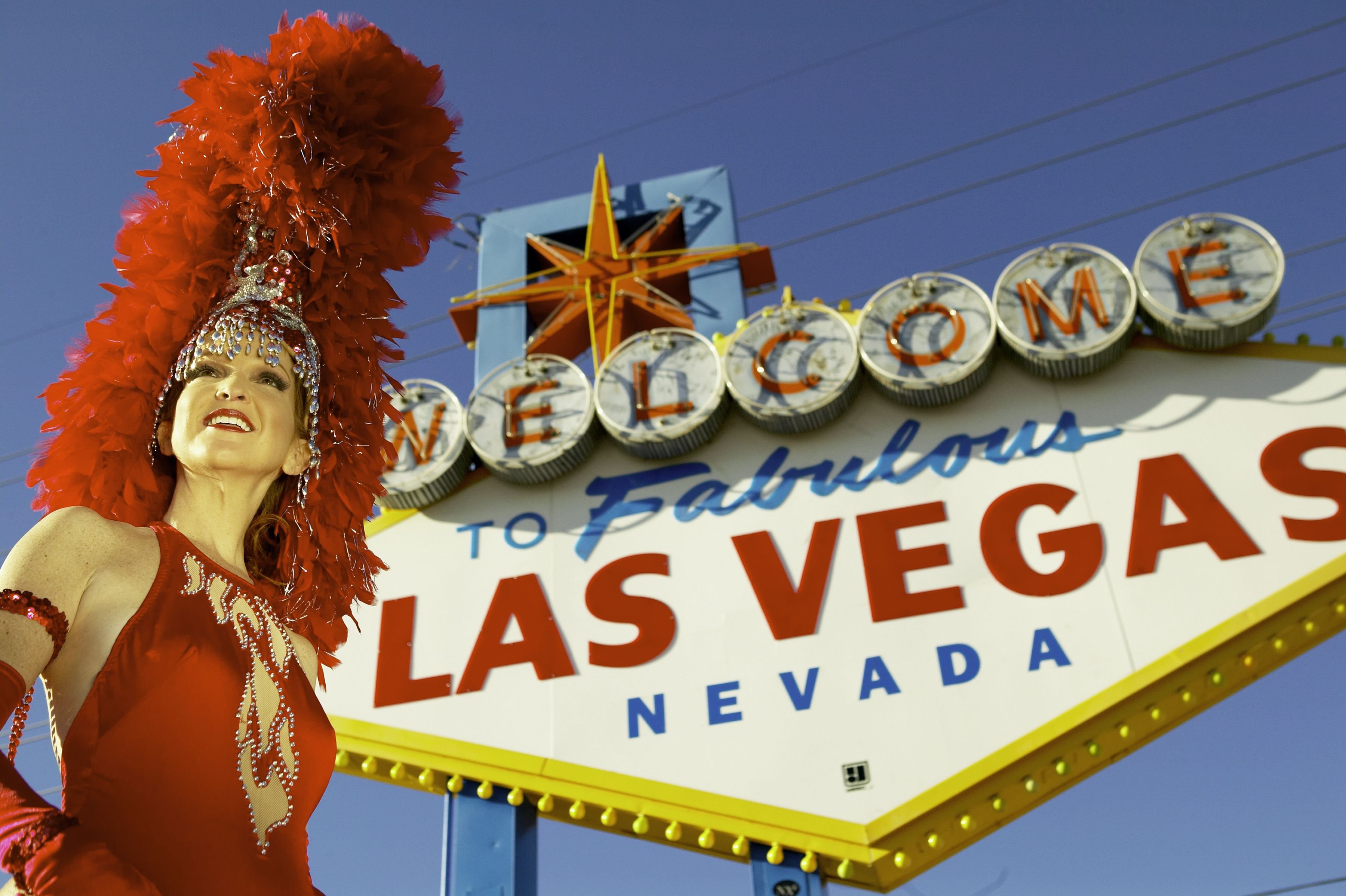 Las Vegas showgirl in front of city welcome sign