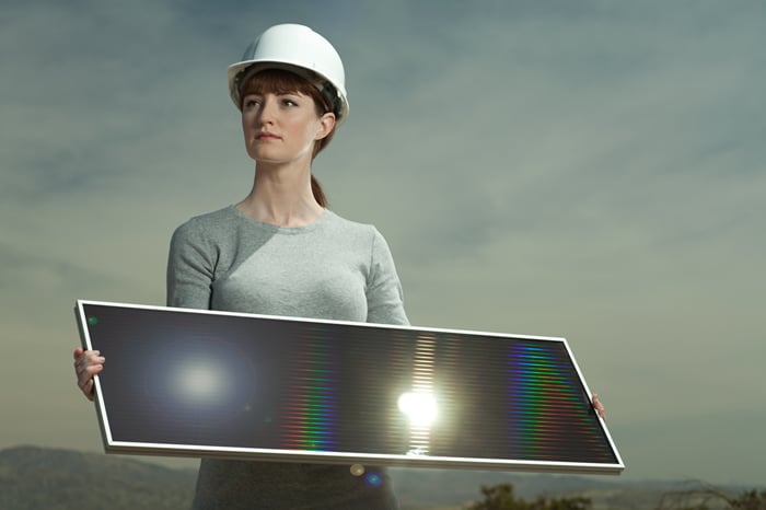 Woman in a hard hat holding a solar panel