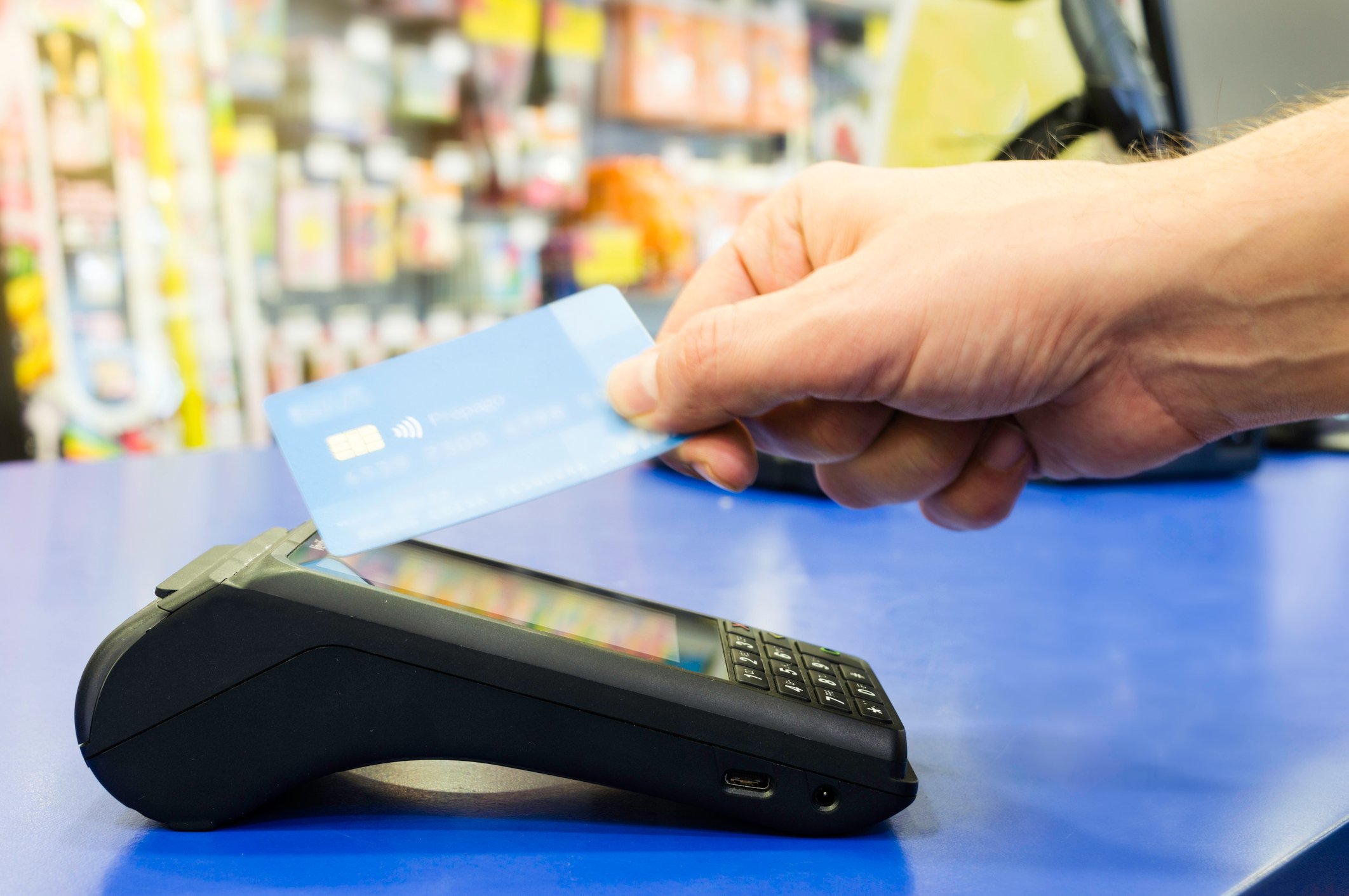 Customer waving a payment card at a reader in a non-contact transaction.