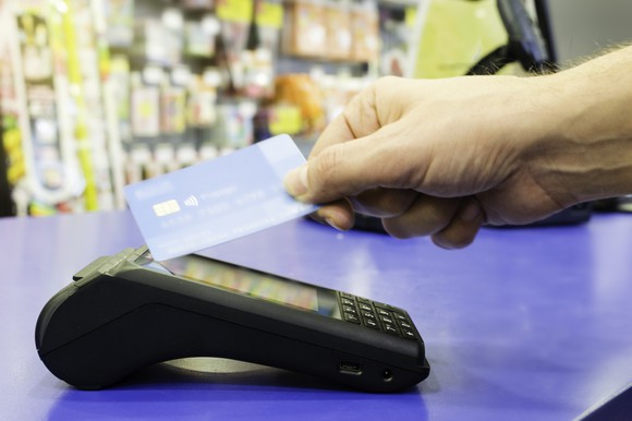 Customer waving a payment card at a reader in a non-contact transaction.