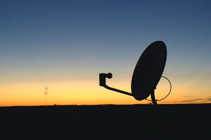 Satellite dishes silhouetted against the horizon in the background.