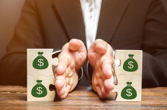 A man separating puzzle pieces with dollar-signs on them.