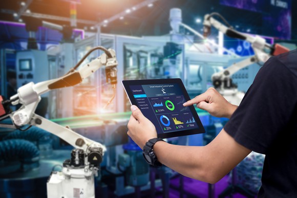 Person in factory controlling robotic arm with tablet