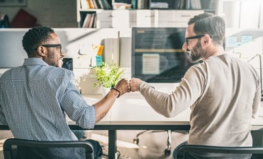 two men at desk fist bump