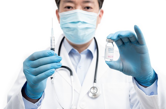 Doctor holding needle and vaccine vial. 