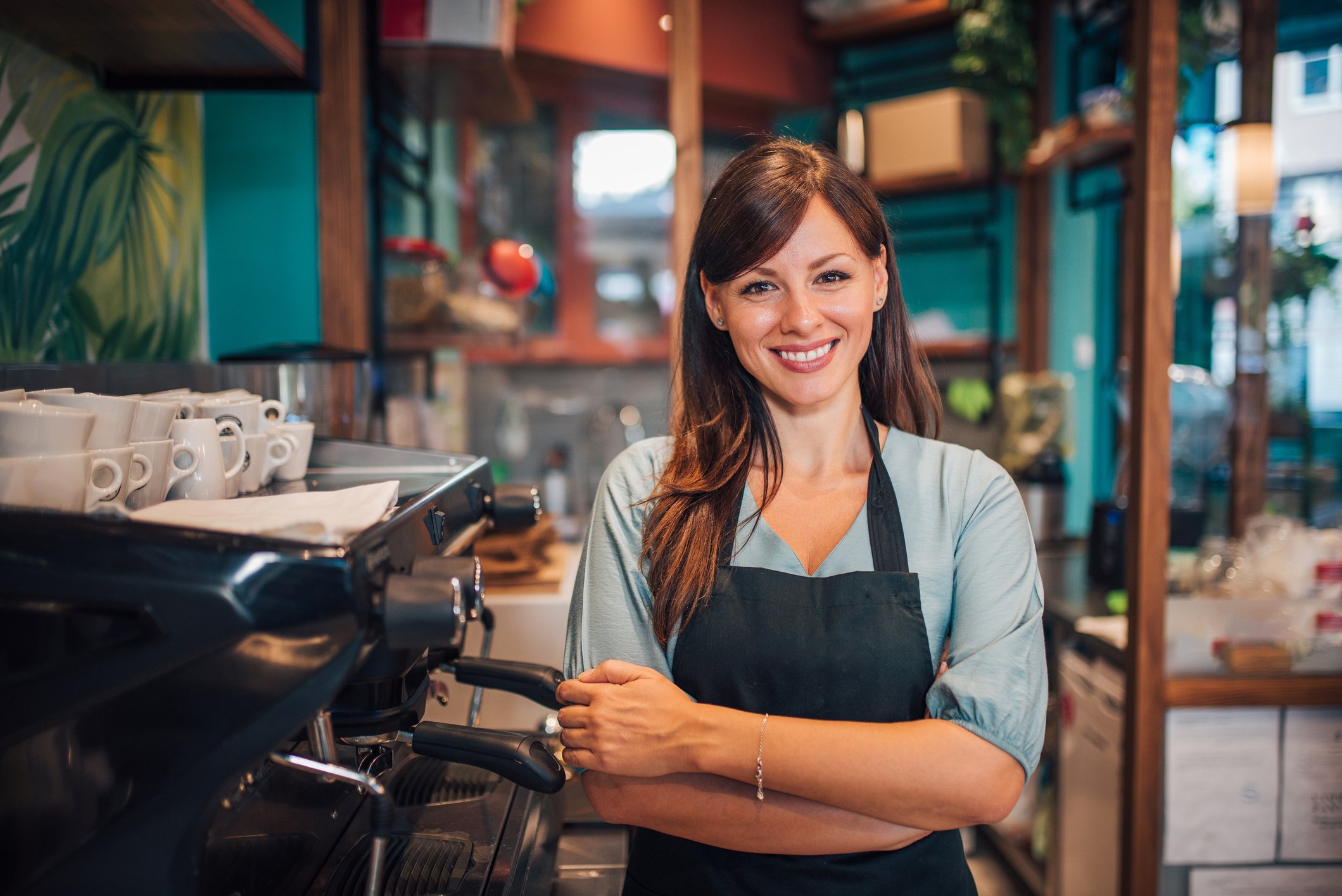 Lady barista smiling beside a coffee machine