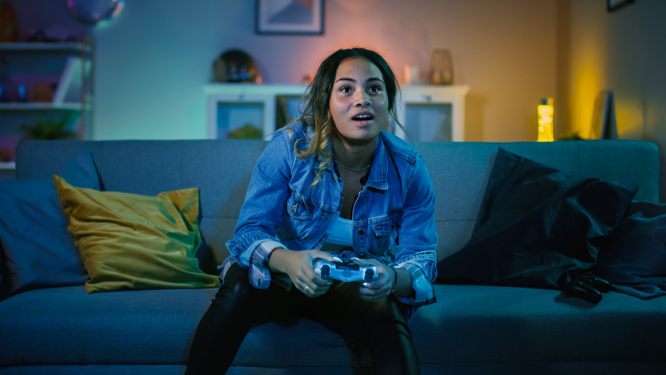 A girl sitting on a couch and playing a video game.