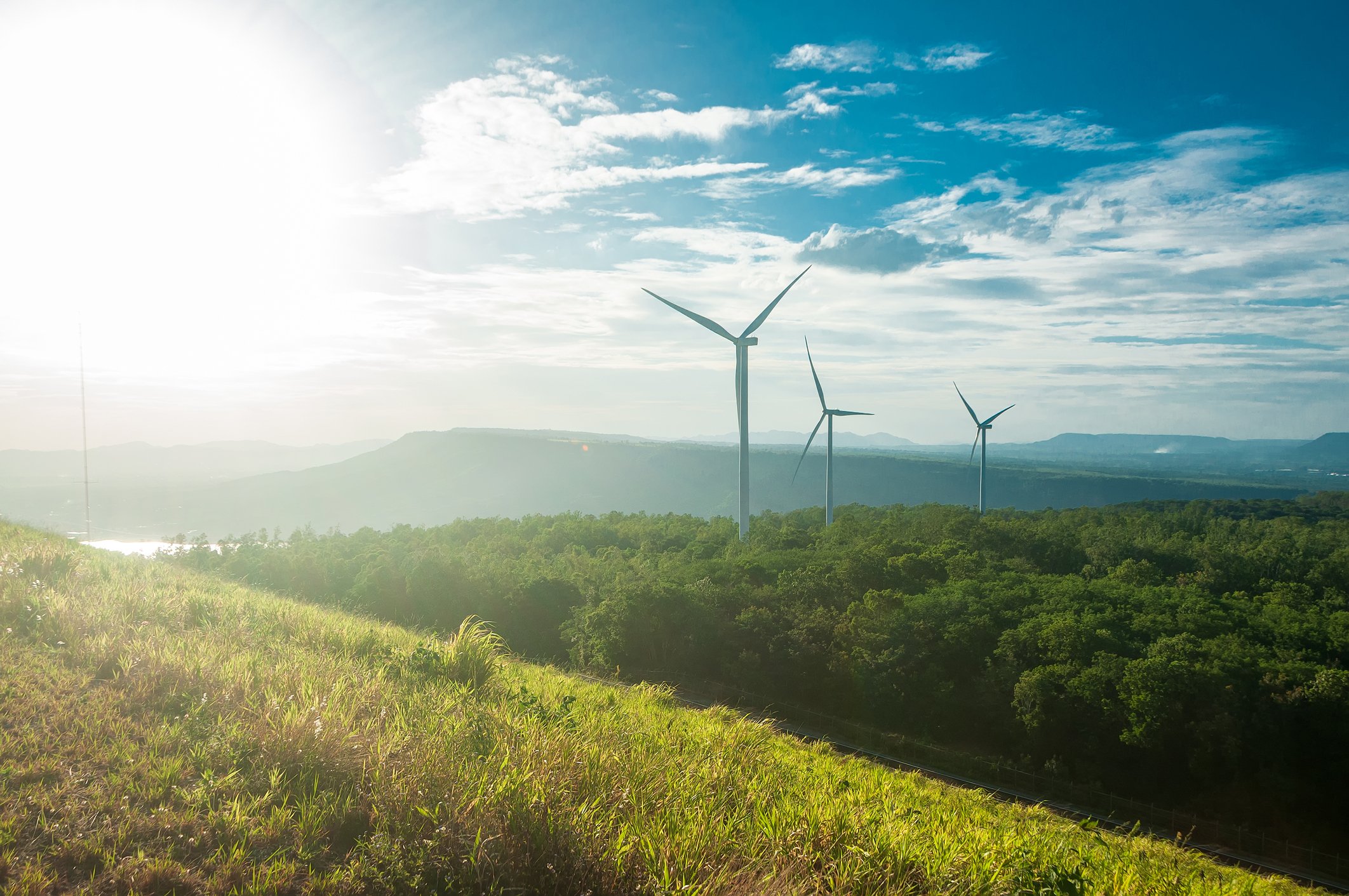 Wind turbines on a hill with a partly cloudy sky in the background. 
