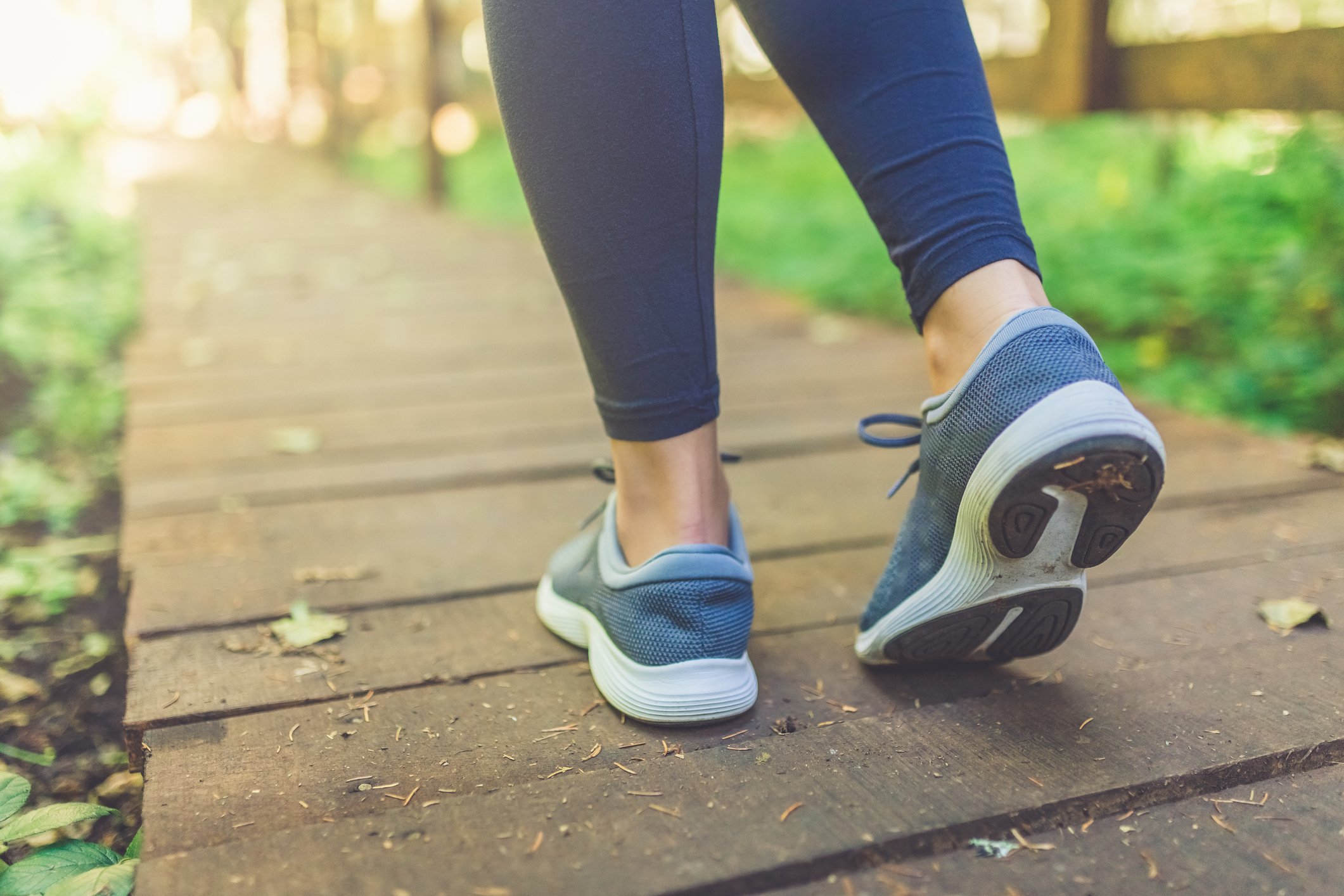 Blue running shoes being worn on wooden walkway