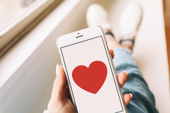 A person holding a phone displaying a heart icon.