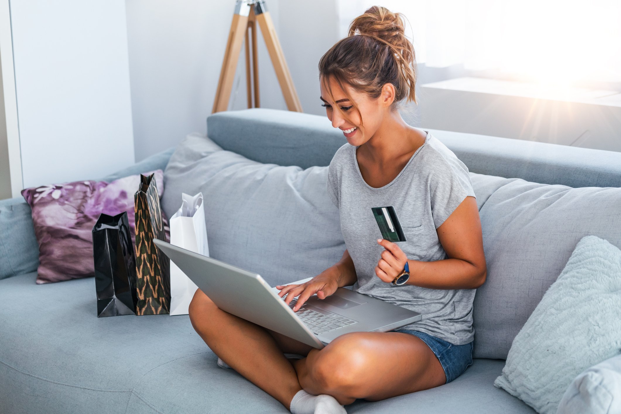 A young woman shops online from her couch.