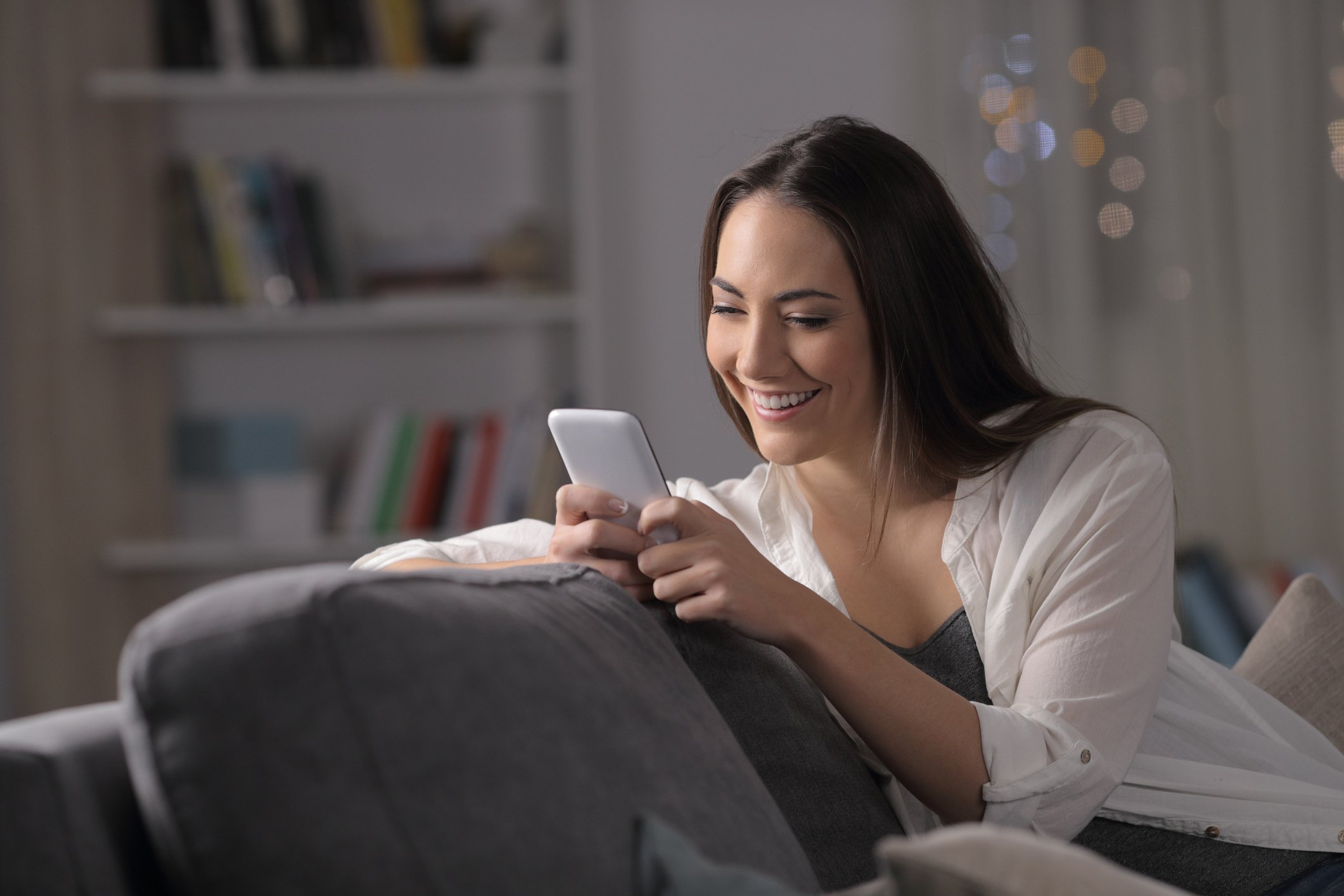 A woman playing a mobile game at home.