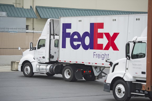 Two FedEx trucks at a distribution center