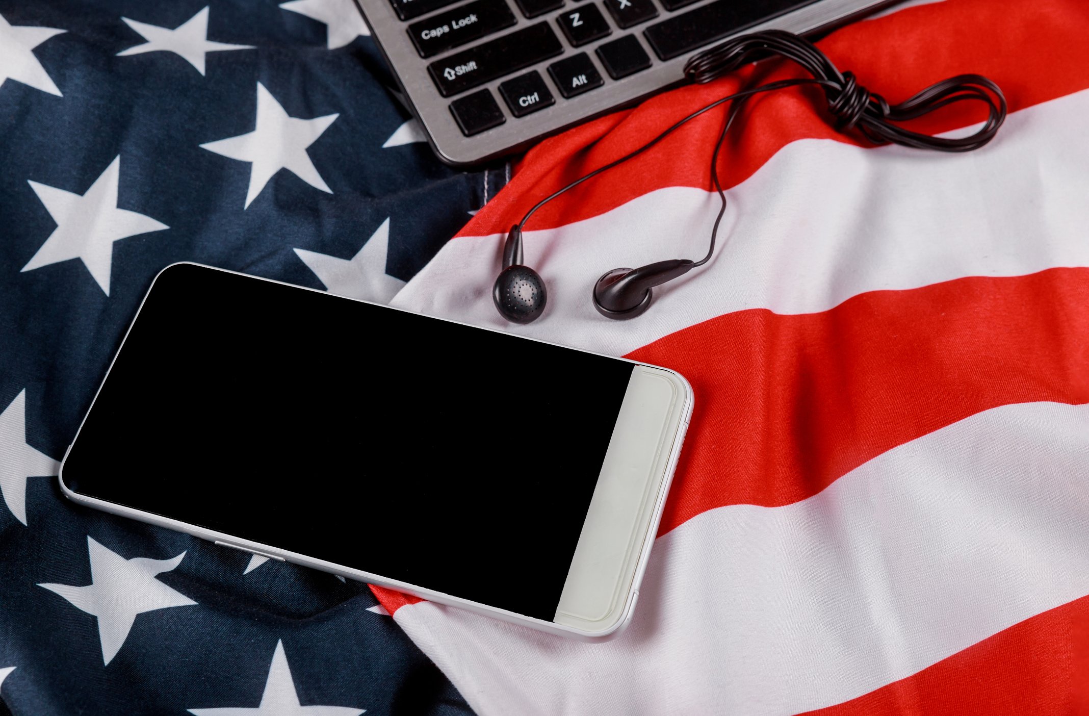 A smartphone and a laptop on an American flag. 