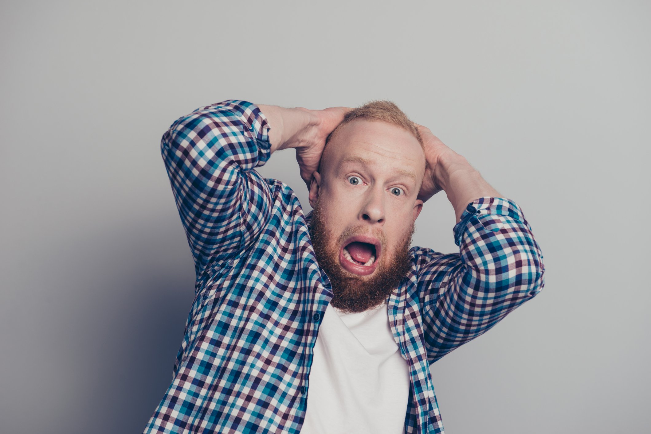 A man with hands on his hand and a scared expression.