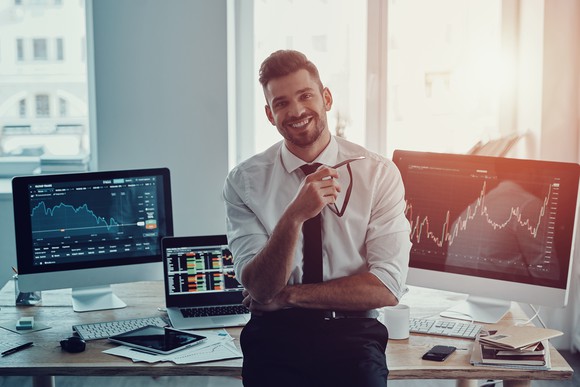 Trader standing by his trading screens. 