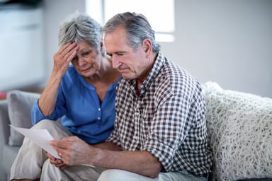 worried older couple looking at documents
