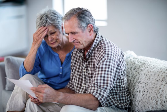 A worried older couple looking at documents