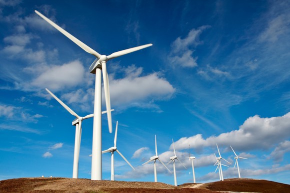A wind power farm against a cloudy blue sky.