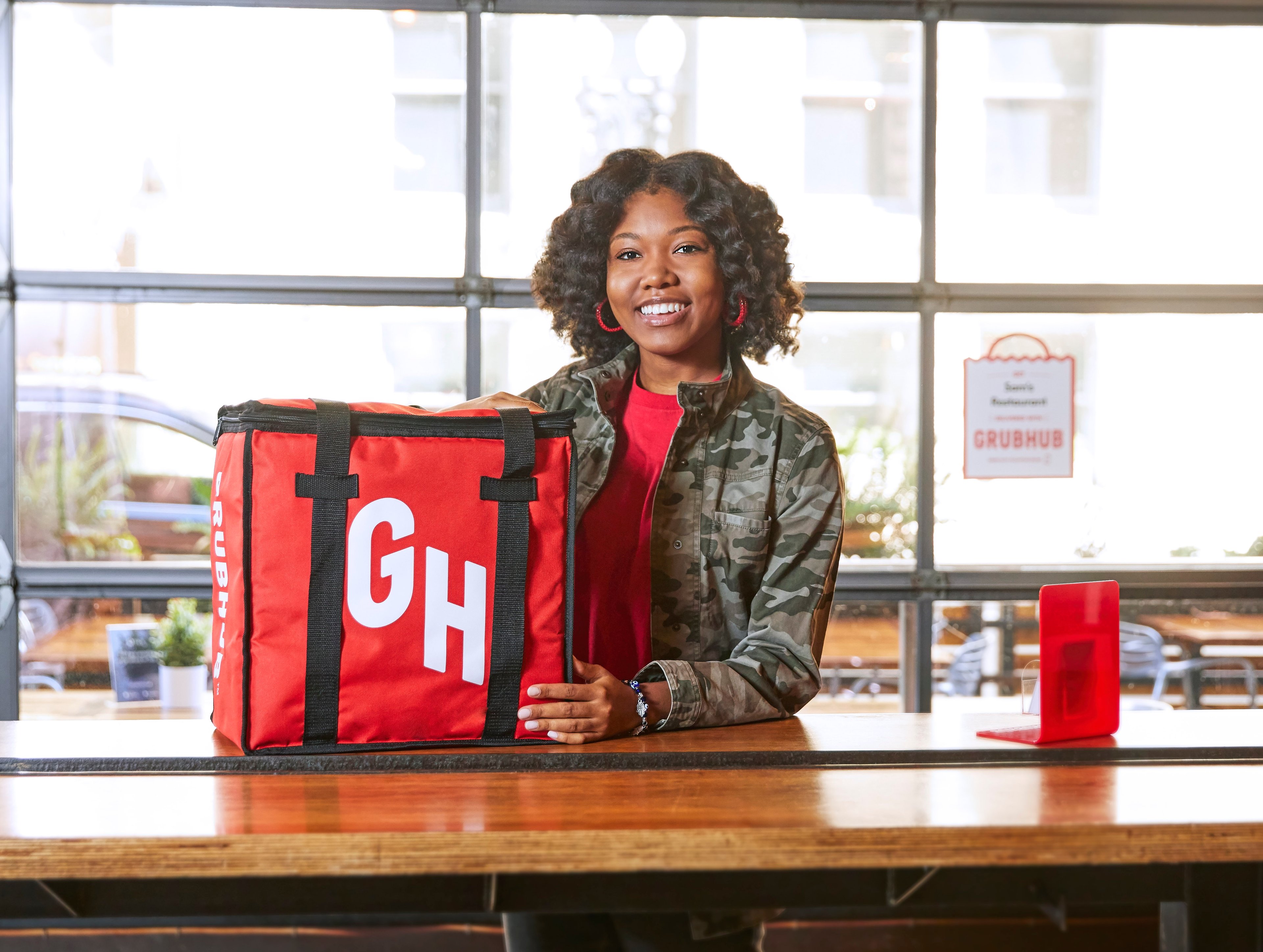 Woman standing with a Grubhub delivery bag