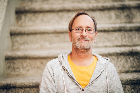 Man in sweatshirt in front of staircase