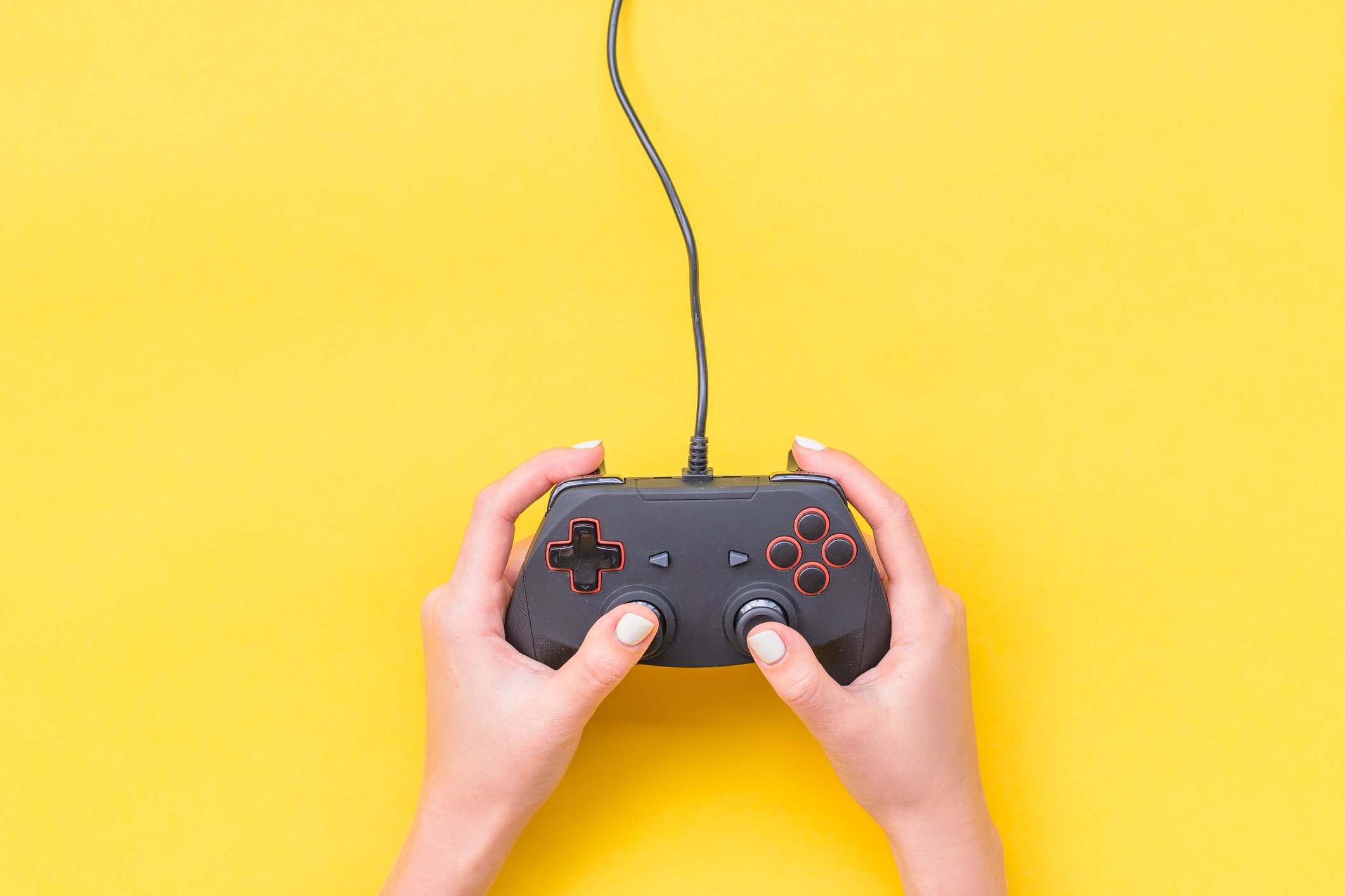 A pair of hands holding a video game controller on a yellow background