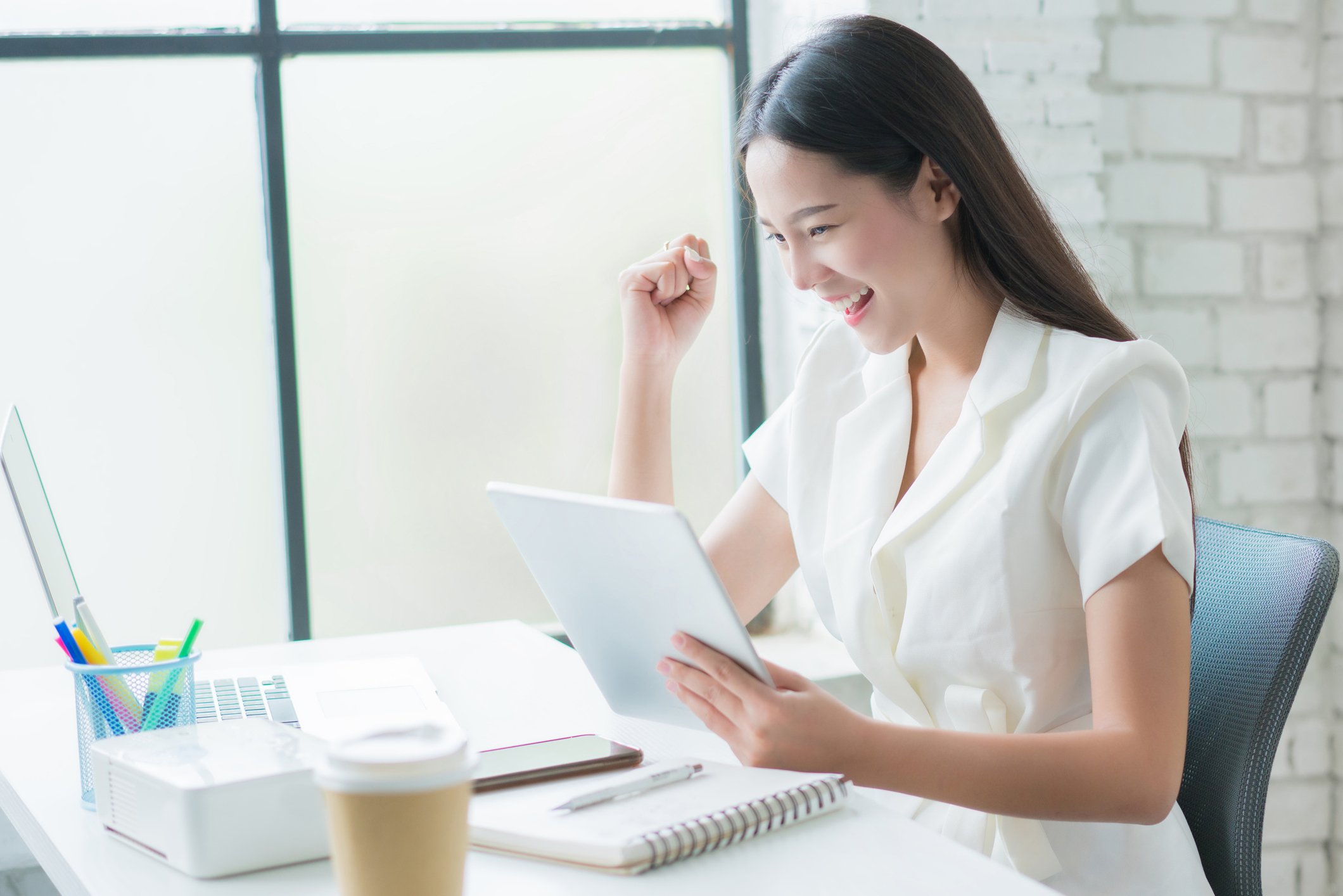 A woman smiles as she looks at her share holdings on her laptop.