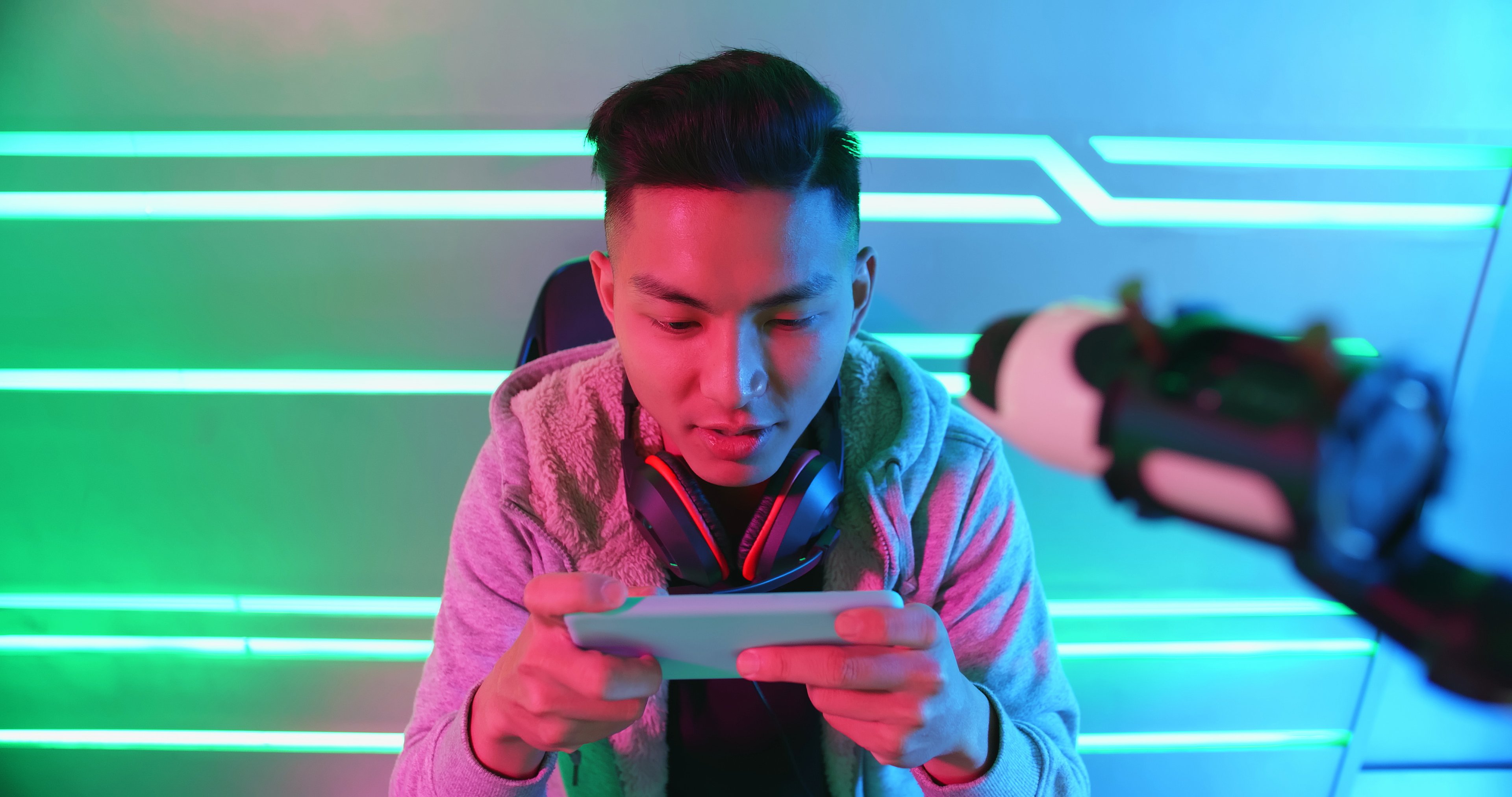 A young man plays a mobile game on a smartphone.