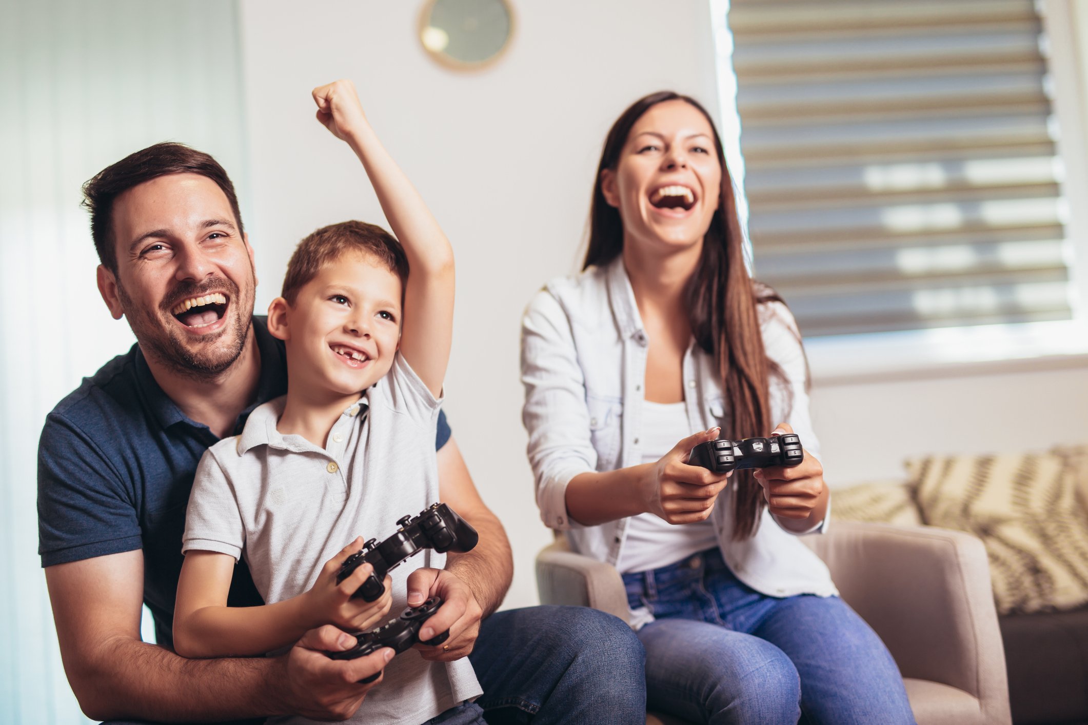 Family holding controllers while they play a game on their console.