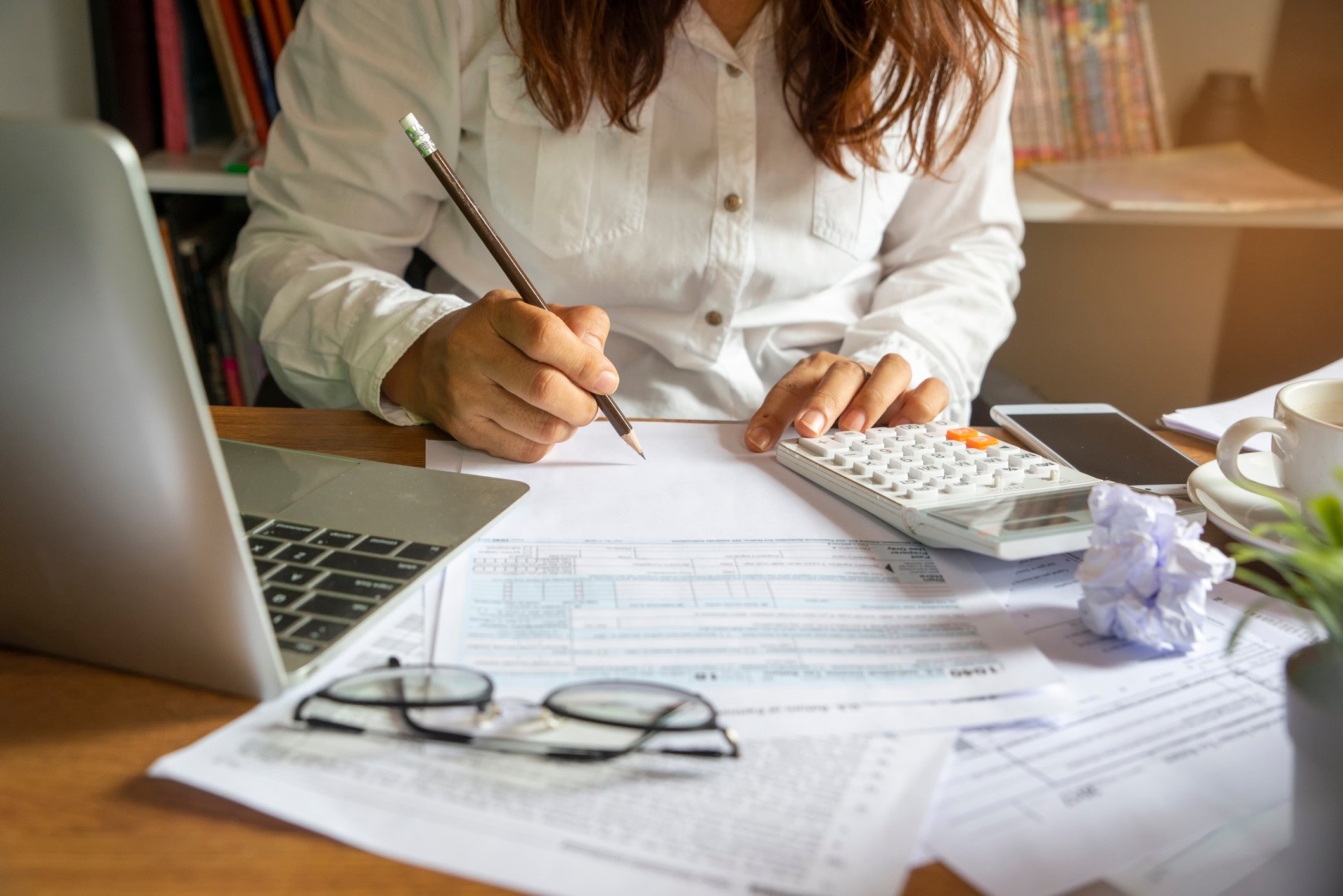 Woman with laptop and calculator filling out 1040 form