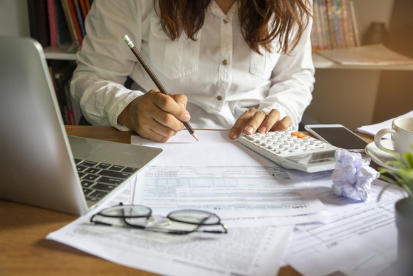 Woman with laptop and calculator filling out 1040 form