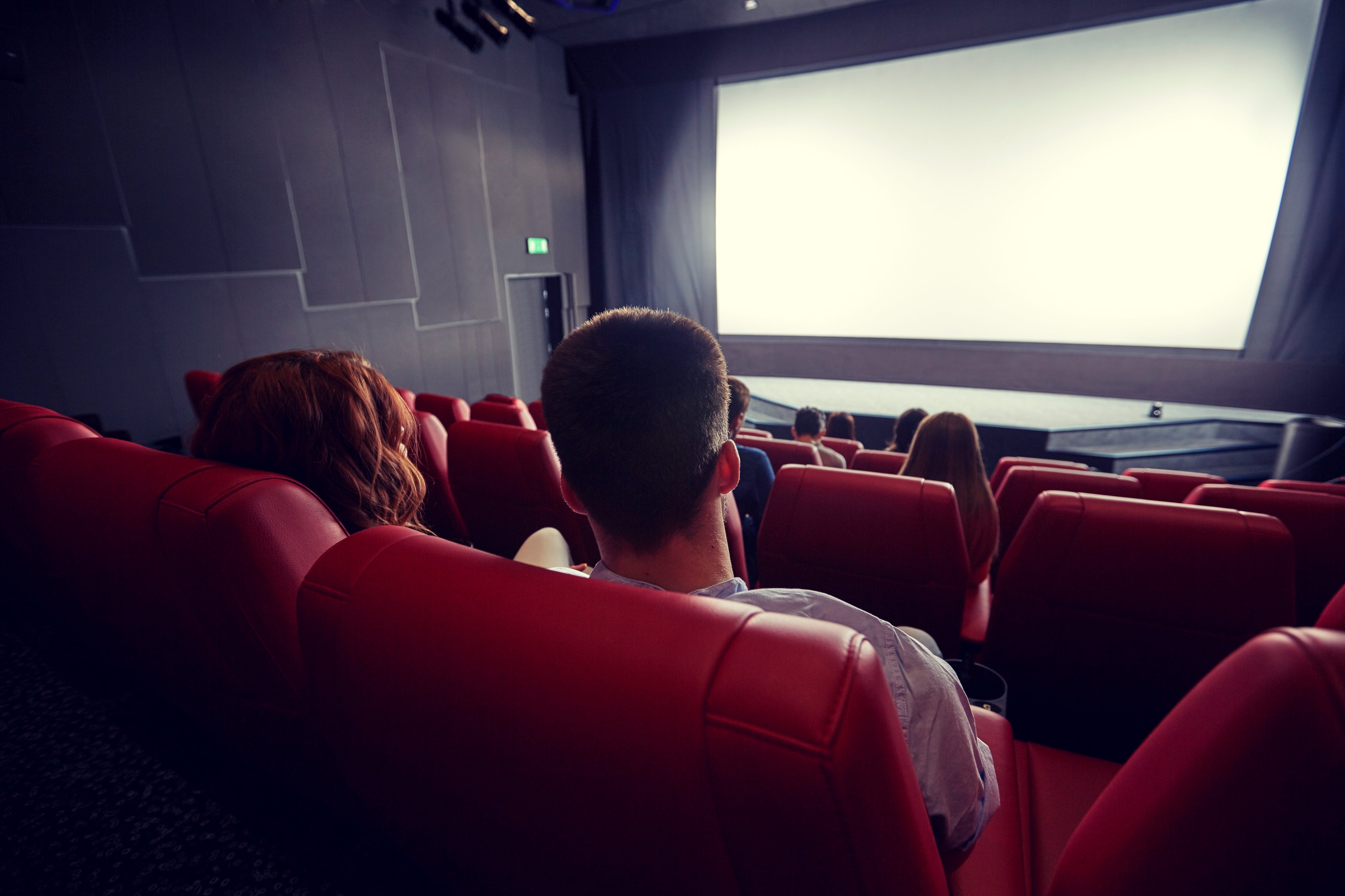 A few people sit in a movie theater.